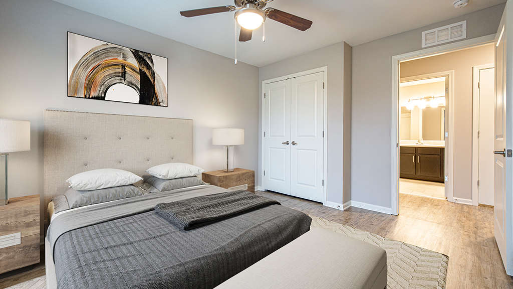Model master bedroom with large walk-in closet, ceiling fan, and access to bathroom